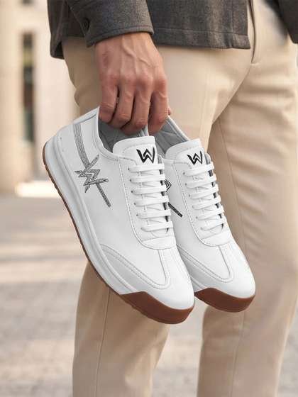 White leather court sneakers held in one hand